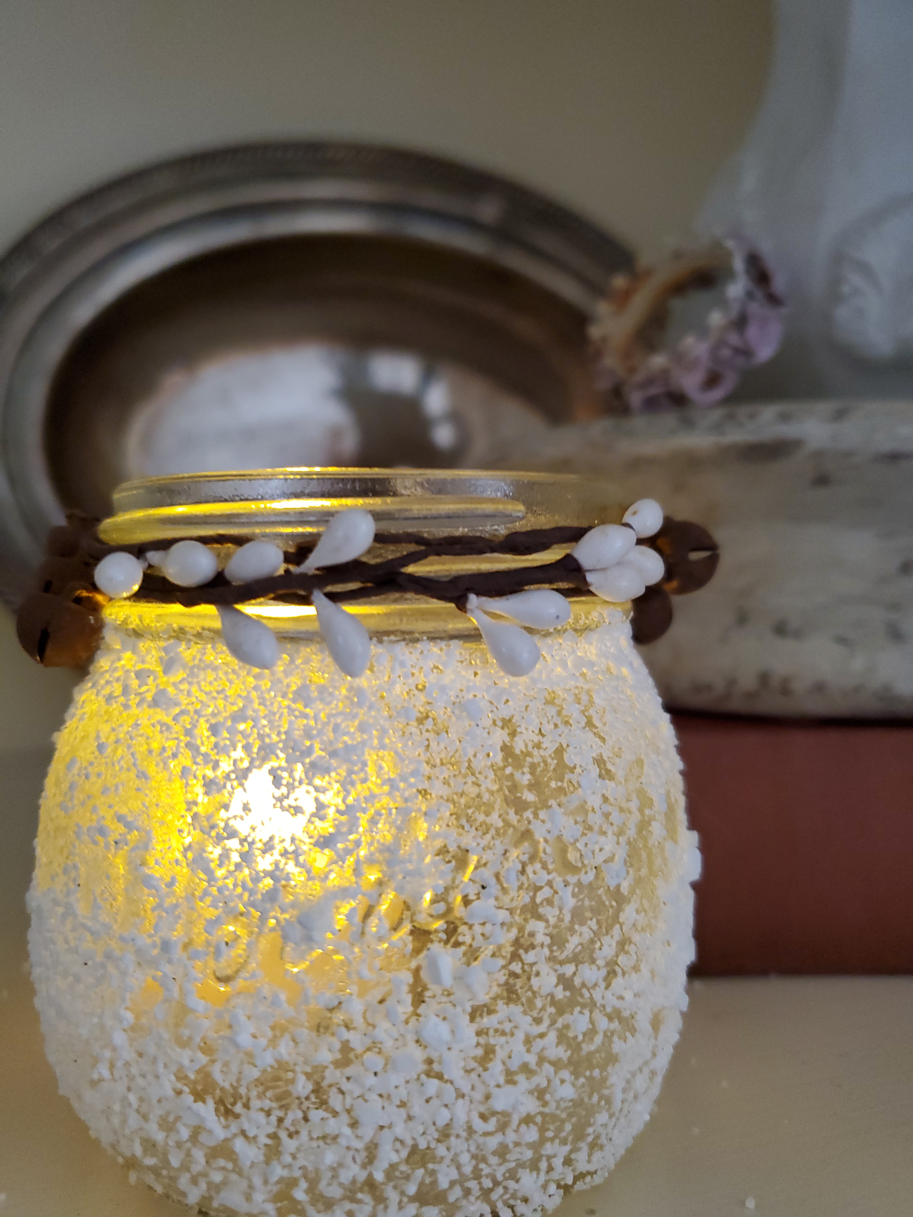 a mason jar covered in fake snow with a candle