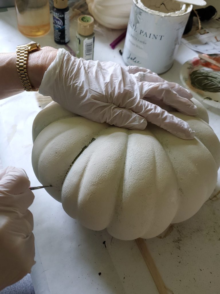 adding dark green lines to the pumpkin for decorating shelves for fall