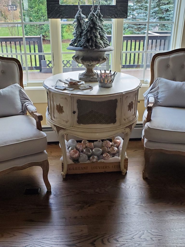 a table with evergreens and crate filled with ornaments underneath