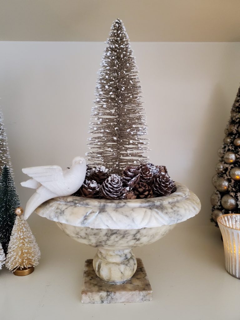mini pinecones in an alabaster bird bath with a bottle brush tree