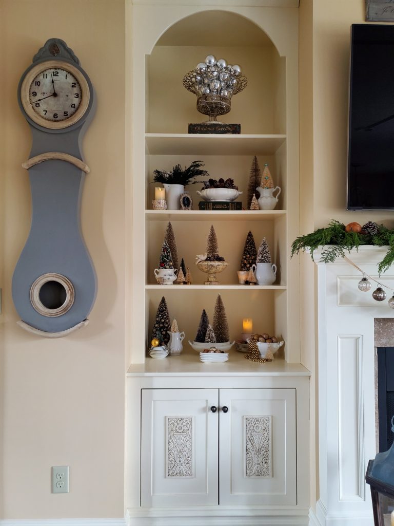 bookcase decorated with bottle brush trees and battery operated candles