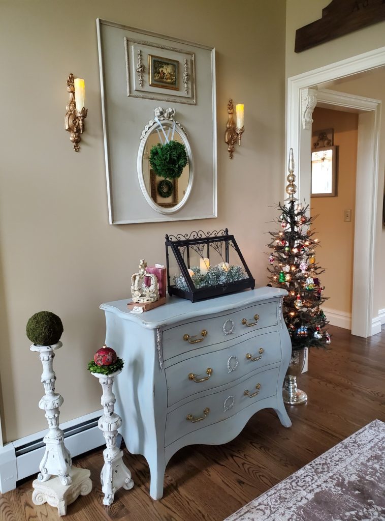 The Christmas foyer with a small tree, books, crown and terrarium with pillar candles