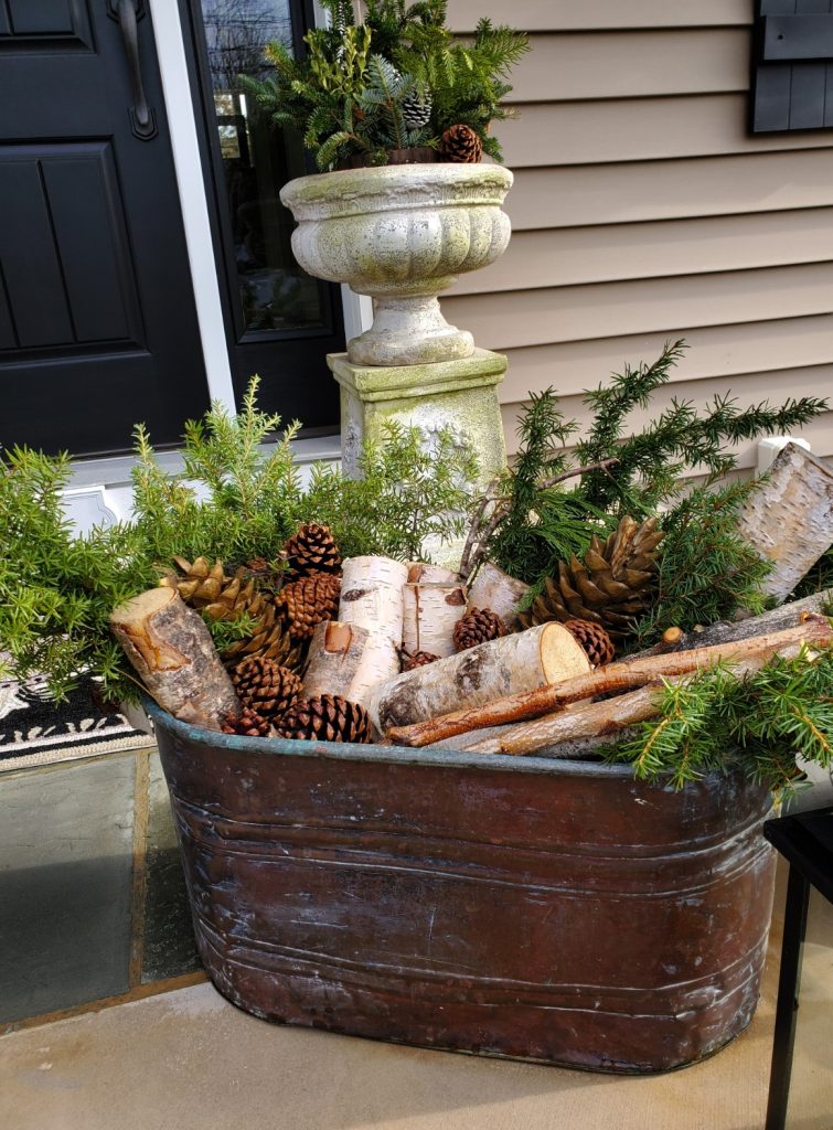 close of antique boiler pot filled with birch logs for the Christmas porch
