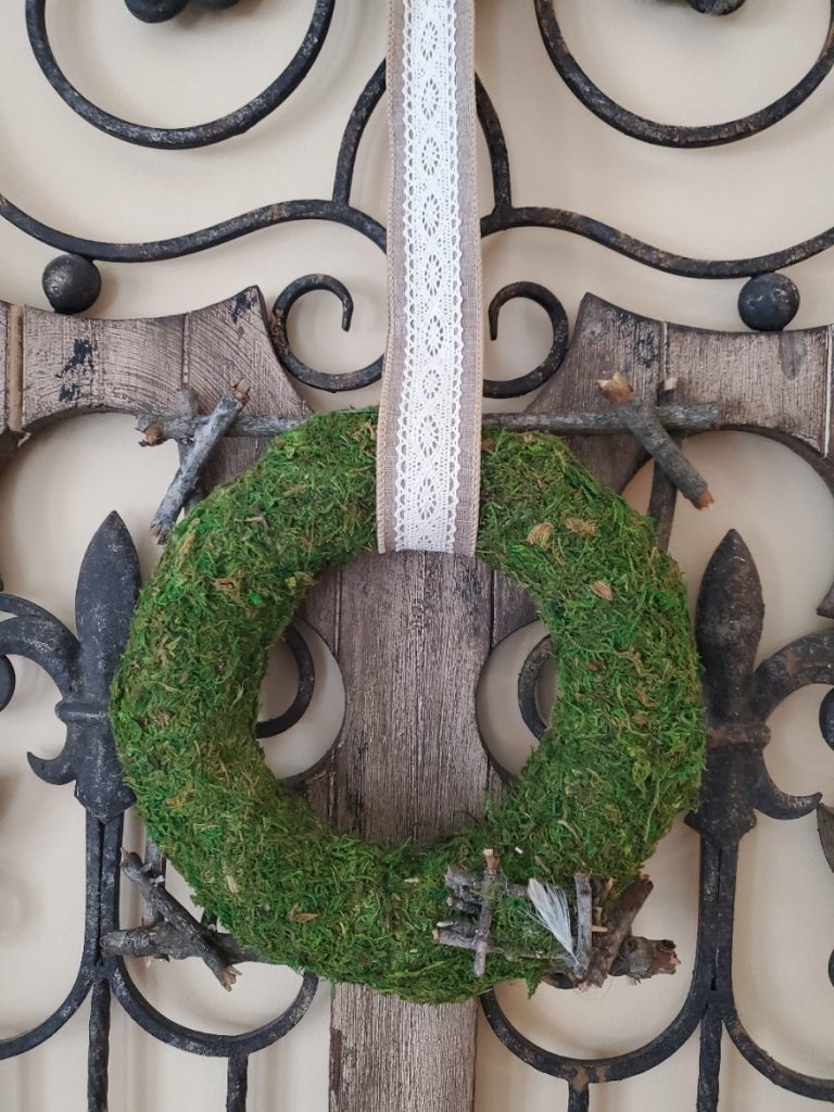moss wreath hanging from an antique shutter
