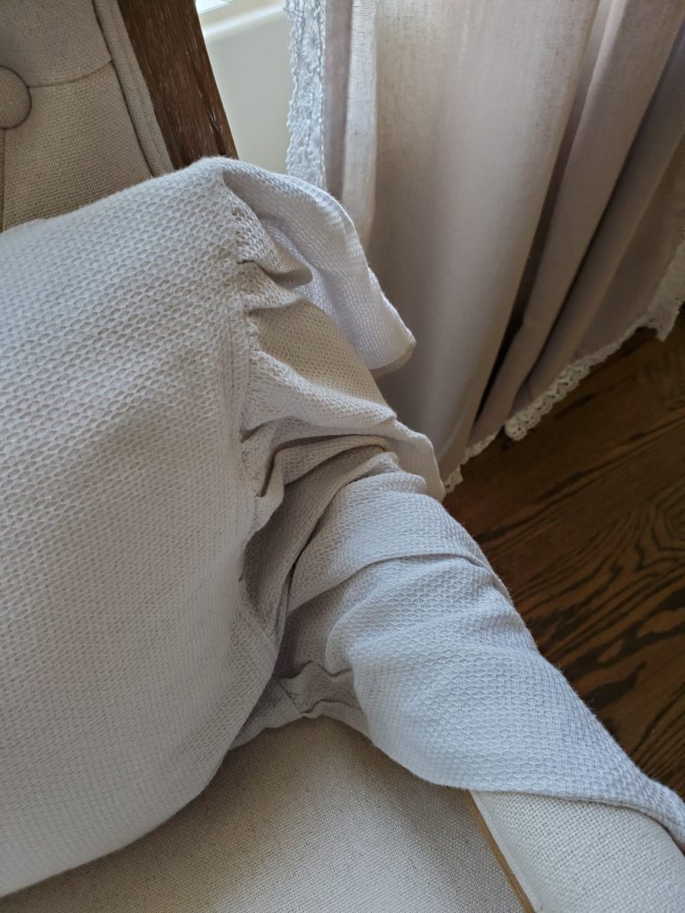 ruffle on the throw pillow draped over the arm of the chair