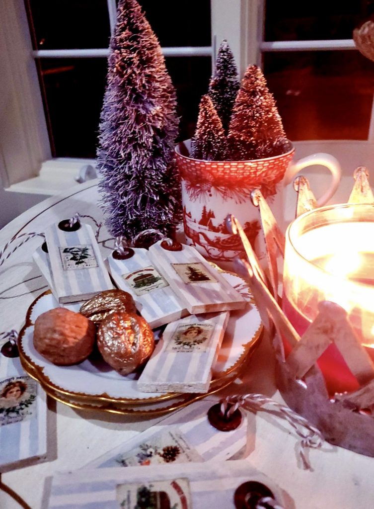 Christmas gift tags with candles lit and bottle brush trees in the evening