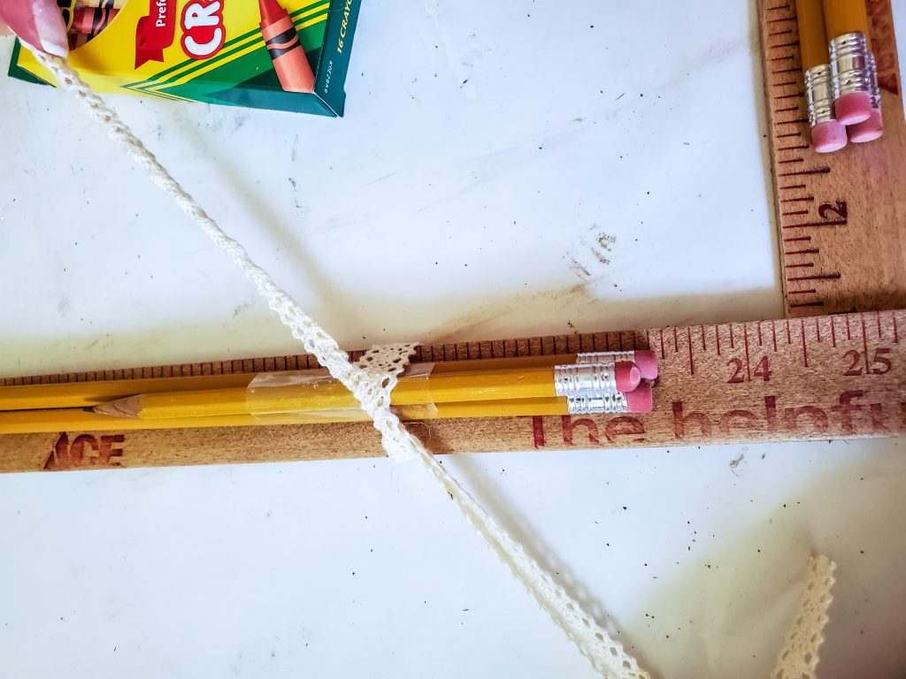 stack of pencils getting tied to the wreath with ribbon