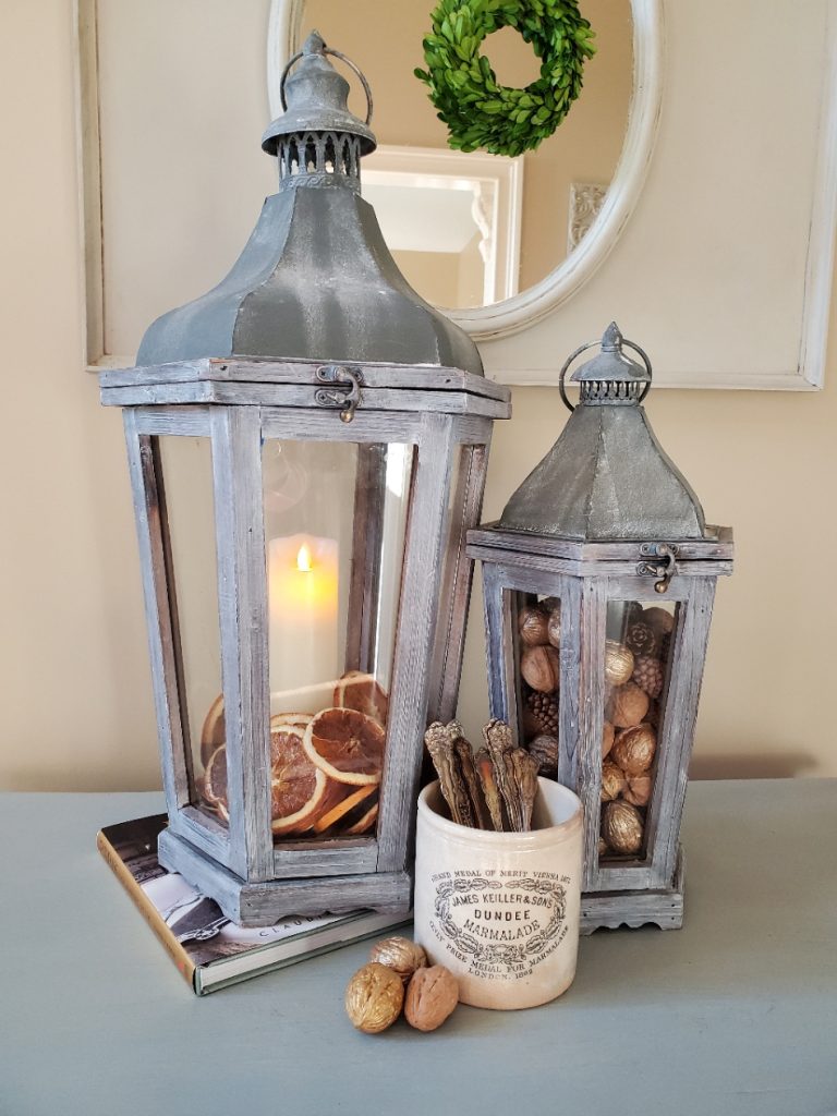 Two lanterns, one with a battery operated candle.  The other filled with nuts
