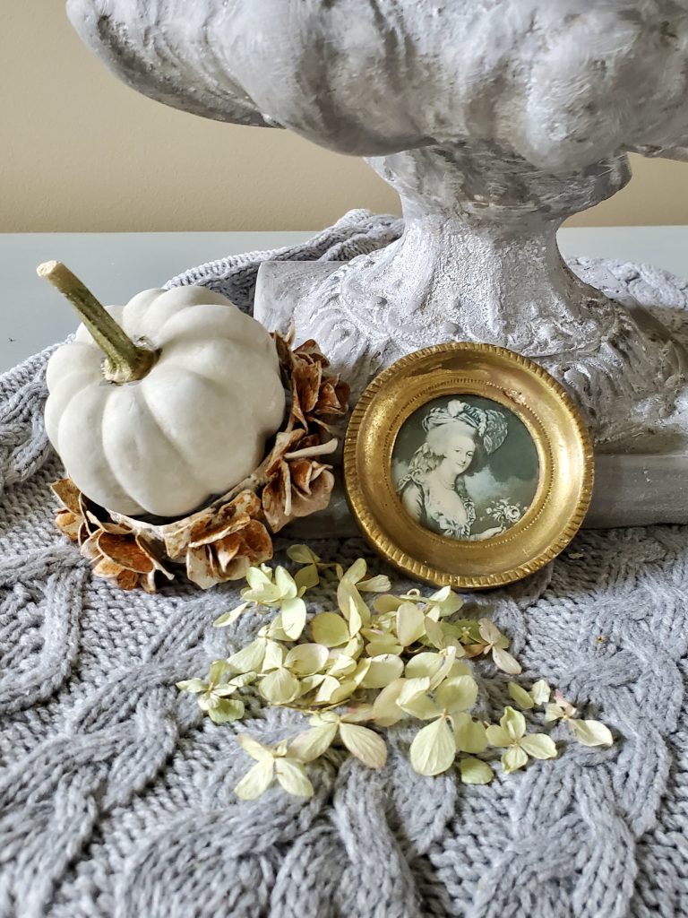 a small pumpkin sitting in a small crown with a Florentine picture and flower petals