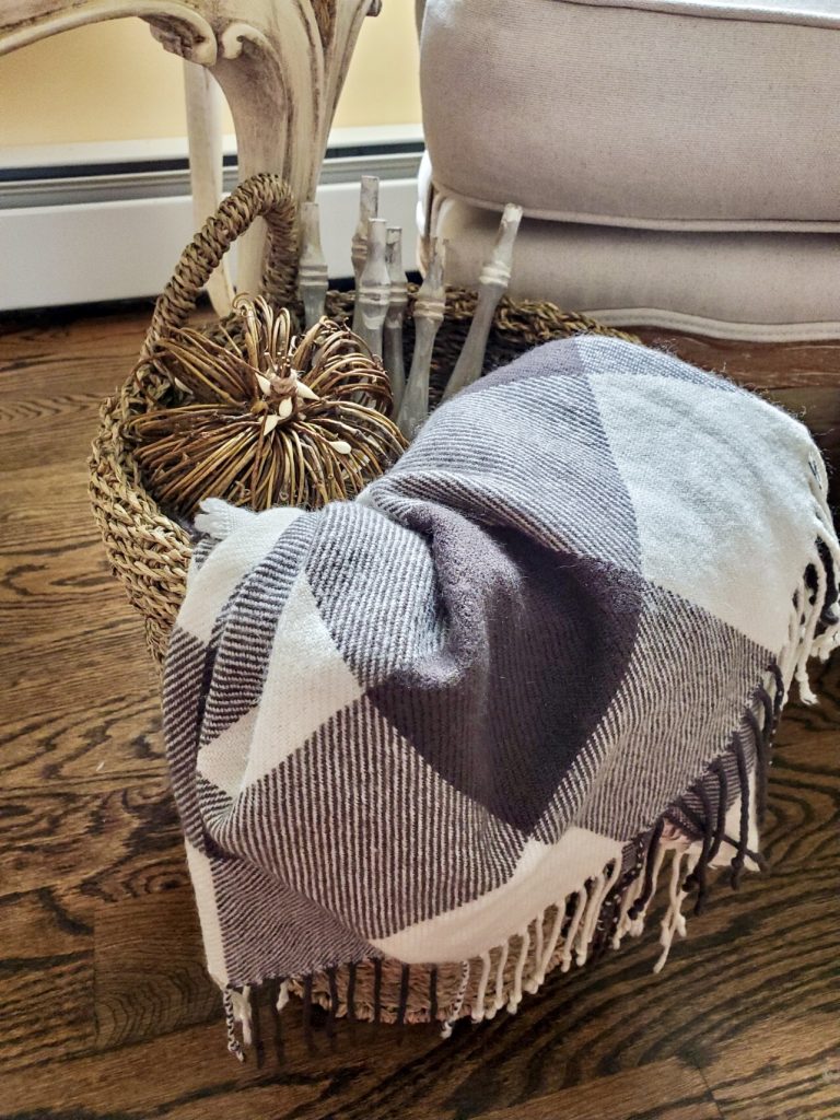 A basket filled with spindles, vine pumpkin and throw adds a rustic look