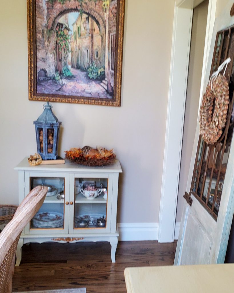 a picture of a small china cabinety and a lantern and wreath for natural fall decor