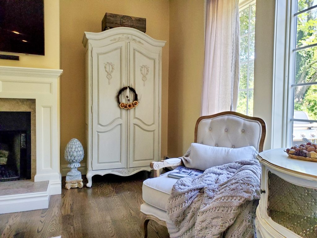 French armoire and one chair and heavy throw blanket in this picture of natural fall decor