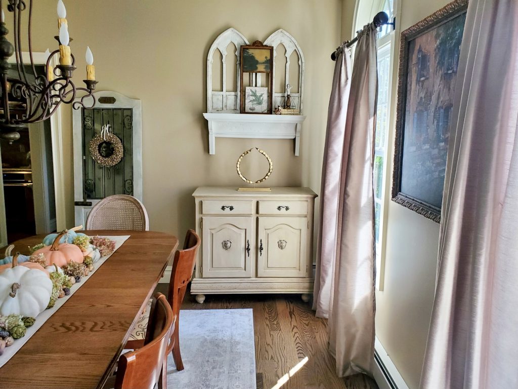 a small buffet with a small mantel above with cathedral shutters and an picture
a door with a wreath for natural fall decor