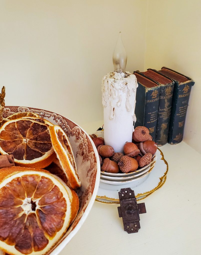 close up the bottom bookshelf of natural fall decor
A candle unlit with books
