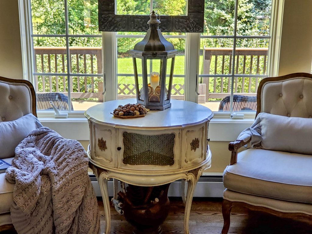 close up chairs by a window. A heavy throw is on the chair arm.
A lantern with fall decor on a table with a tray