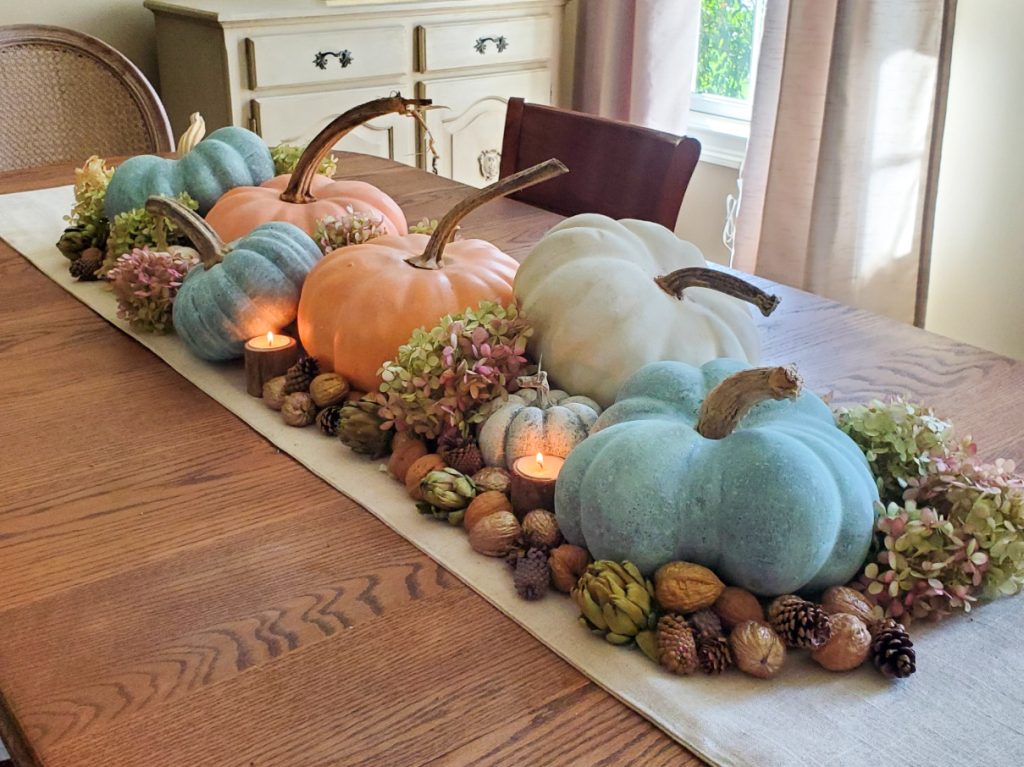 centerpiece on dining room table with an assortment of pumpkins. Green, white and peach pumpkins.
with natrual fall decor of dry hydrangea