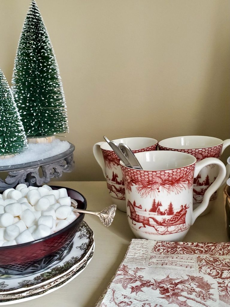 close up of marshmallows in a red bowl and mugs and napkins on the hot chocolate bar