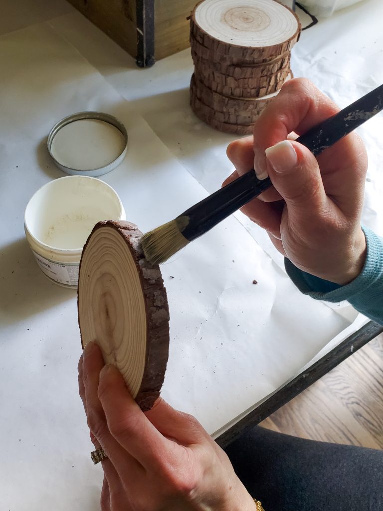 adding the white wax to the bark of the wood coasters