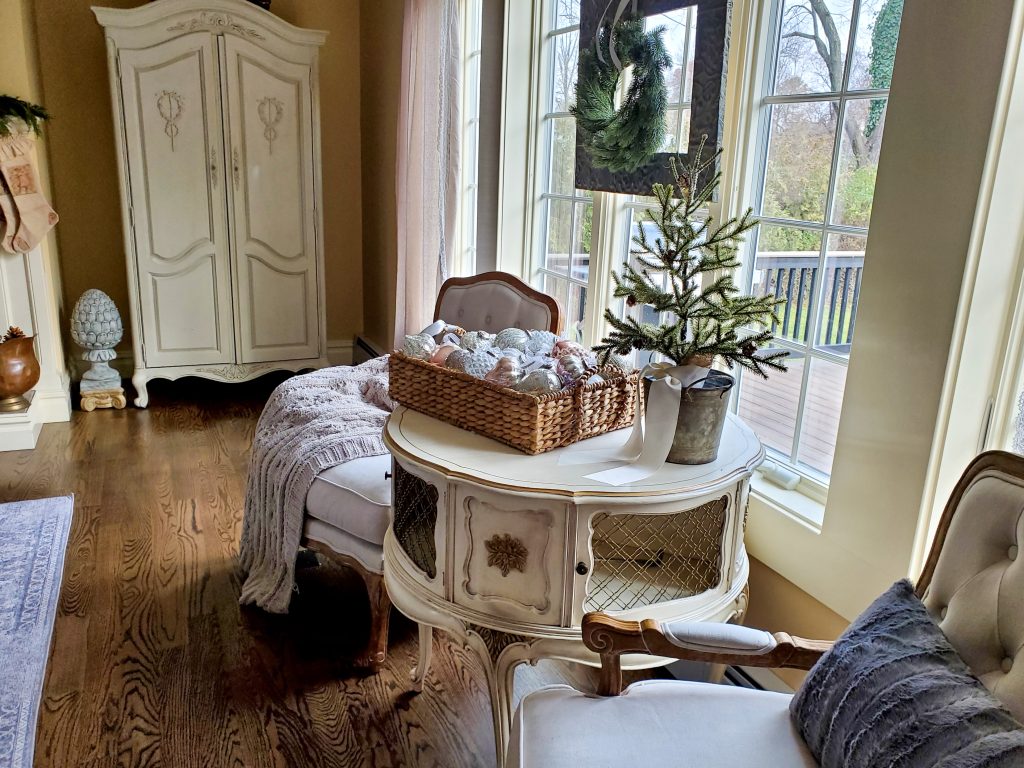 French chairs with dark gry fur pillows. A basjet filled with ornaments from Balsm Hill and seedling evergreen tree.
And a French table in our French Christmas