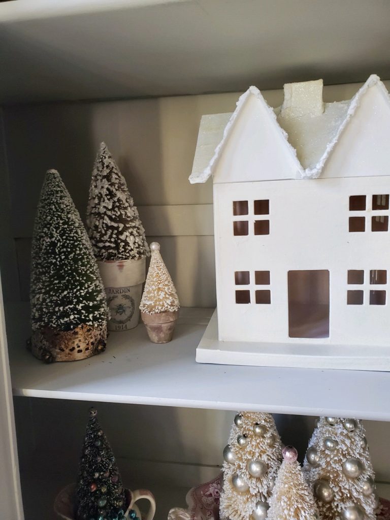 a white house with bottle brush trees in flower pots and a crown for a vintage French Christmas