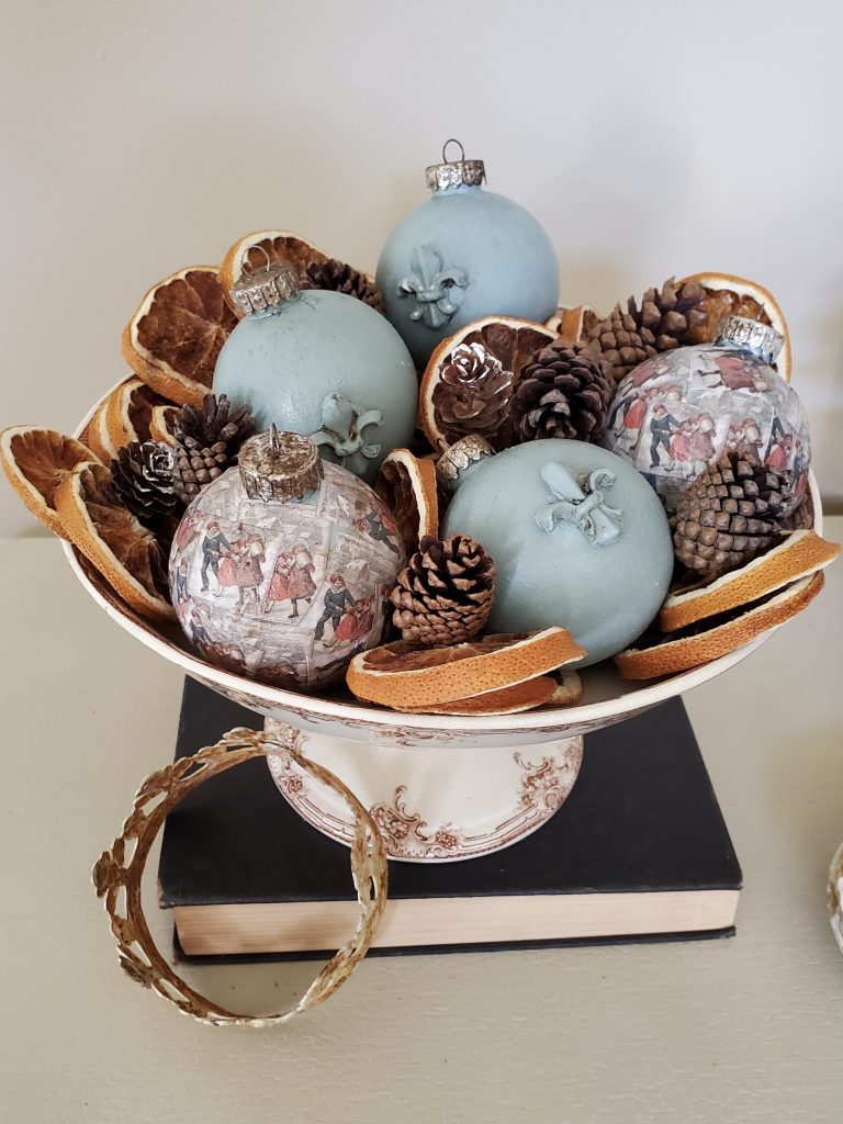 a dish holding christmas balls on a book with a crown for christmas time in the dining room