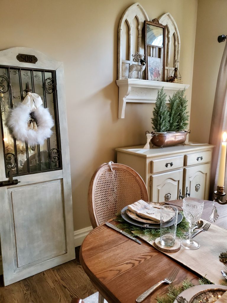 a door leaning againt the wall with a fluffy white christmas wreath