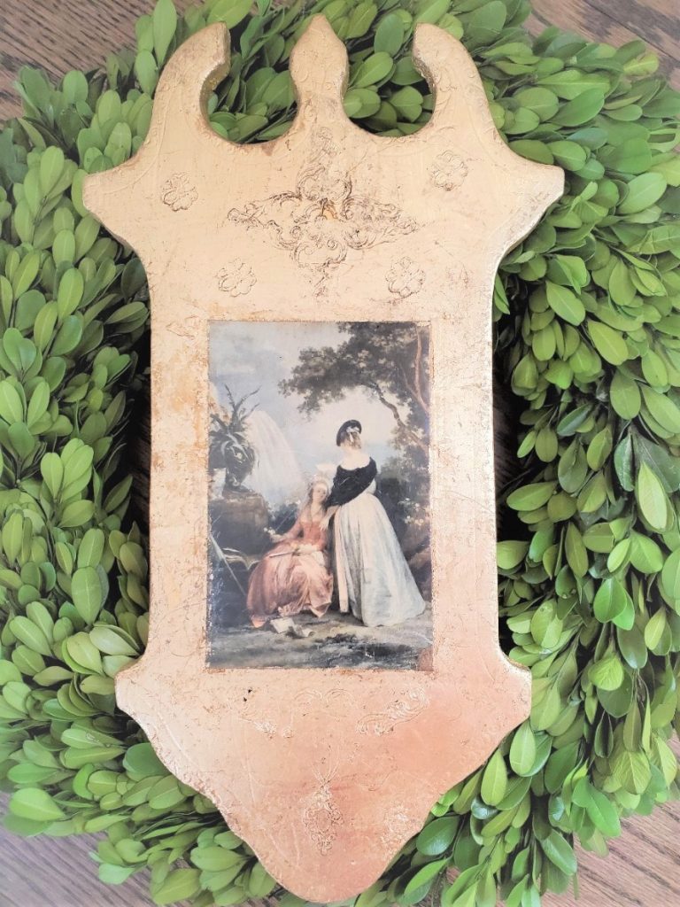 a Florentine plaque inside a boxwood wreath