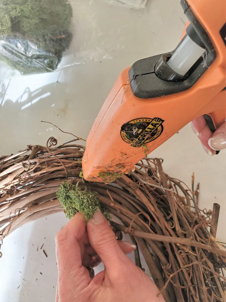 adding hot glue to the moss