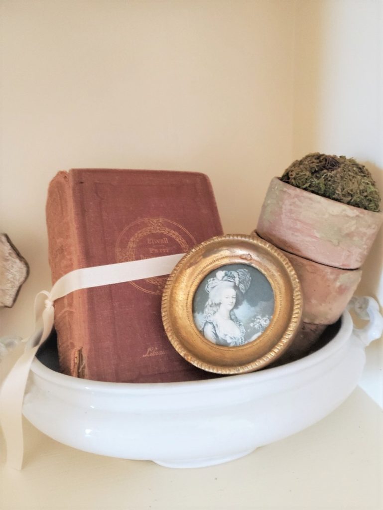 Spring decorating with flower pots and moss ball.  An old book and a small Florentine picture in a tureen bottom