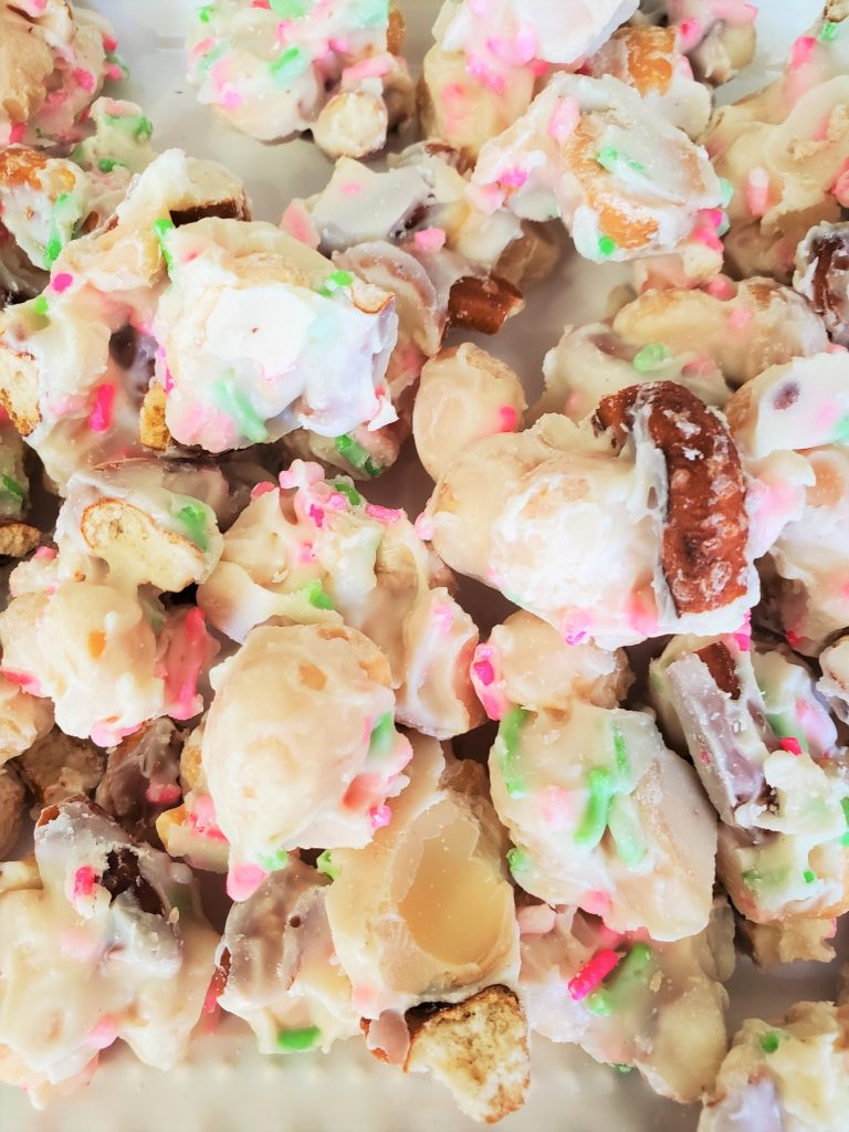 white chocolate covered macadamia nuts with pretzels and pink and green sprinkles