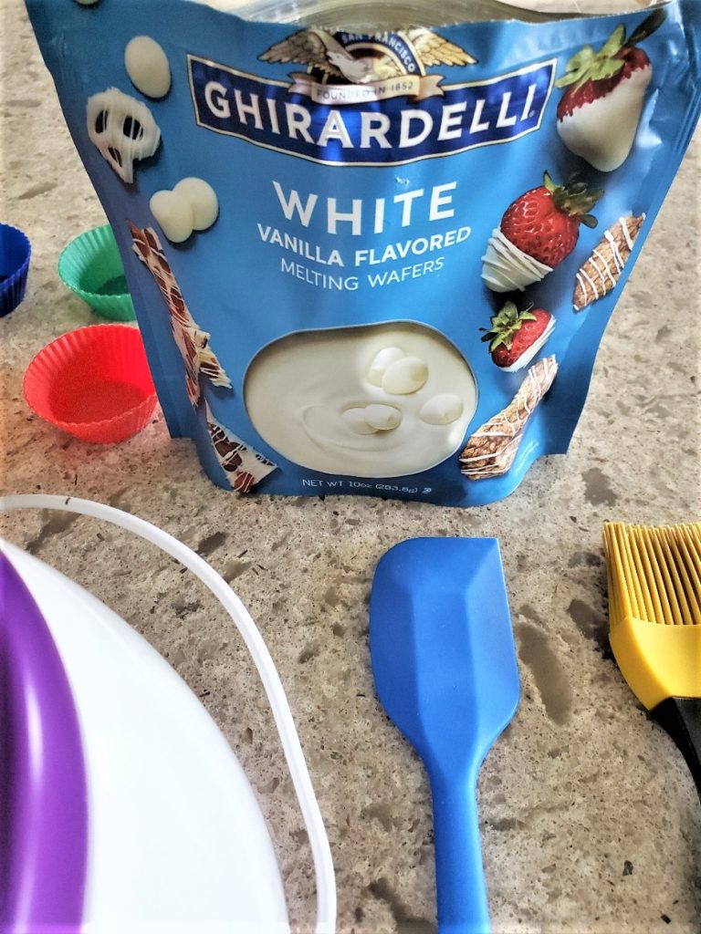 white chocolate melting wafers, silicone spatula and silicone pastry brush