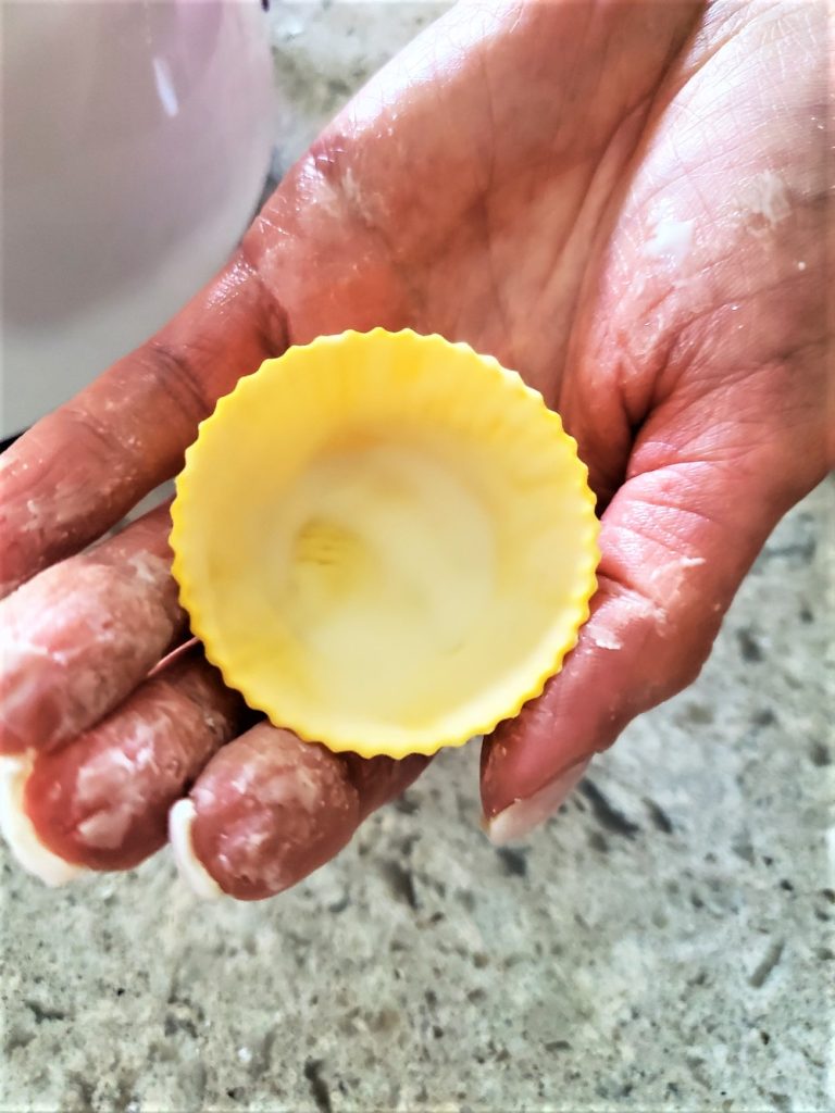 me holding a cup with one layer of the candy added to the cup