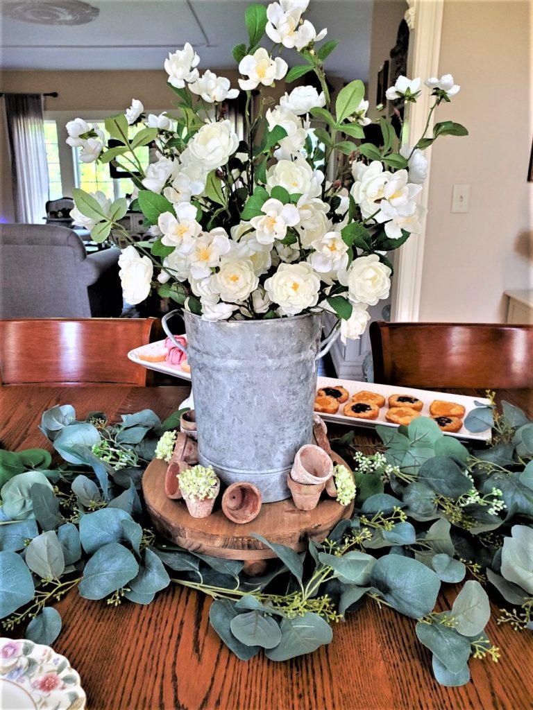 centerpiece of white wild roses, A wood riser with small terracotta pots around it.