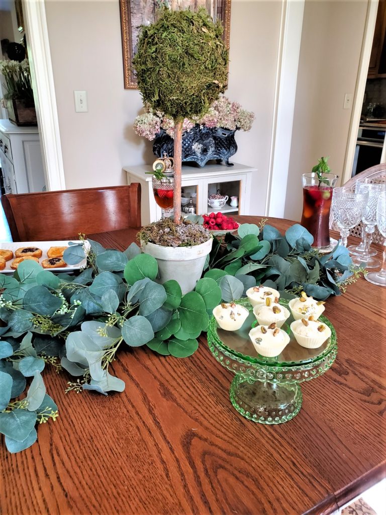 Everything You Need for an Amazing Indoor Garden Party cake plate filled with small desserts.  

Caraf filled with iced tea Sangria and a topiary
