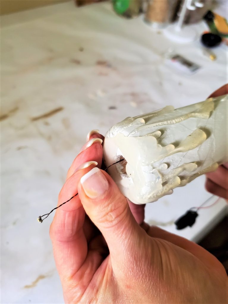 pulling the light bulb through the opening of the candle DIY