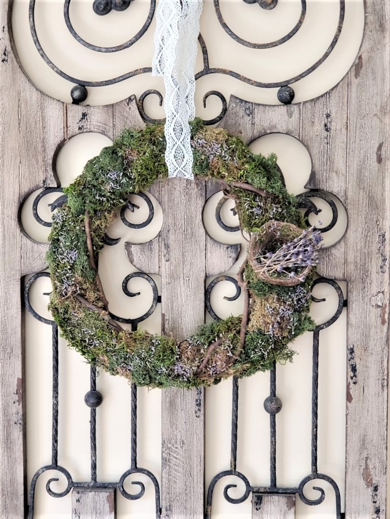 a moss, grapevine, dried lavender wreath with a bird nest filled weith small lavender sprigs