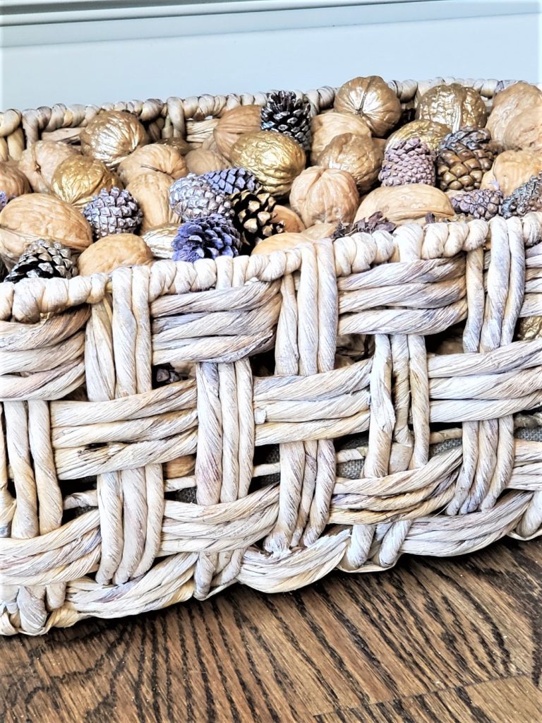 Another old looking basket filled with walnuts in the shell and a variety of pinecones