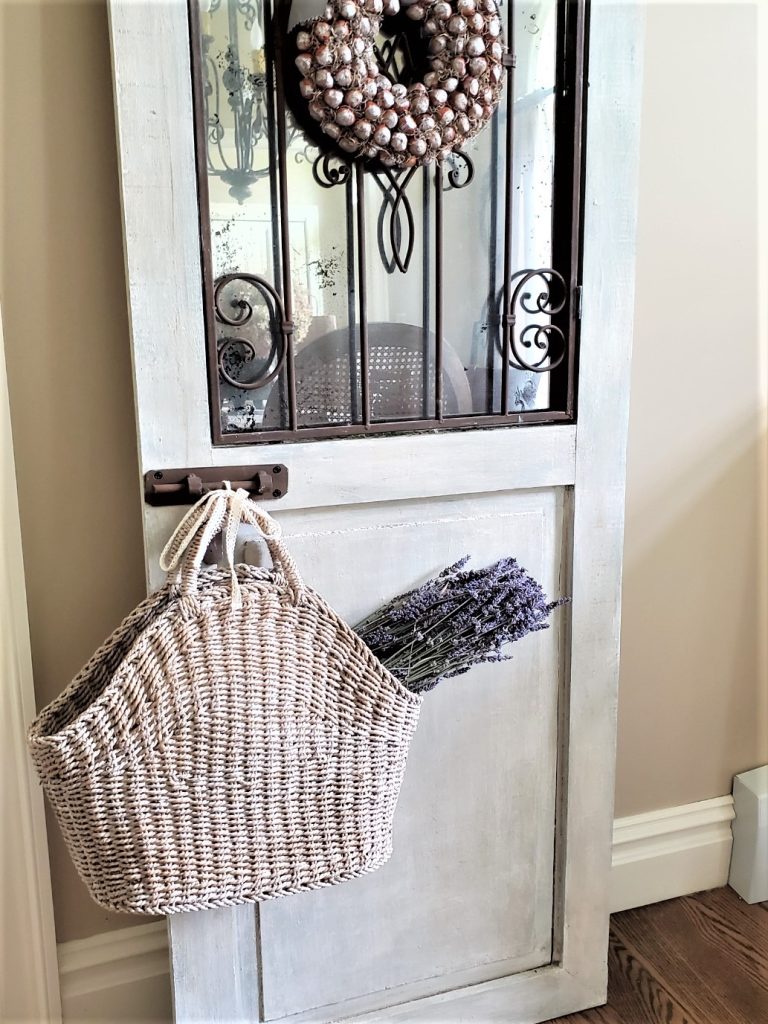 an old door with a basket hanging and filled with dried lavender for basket decor ideas
