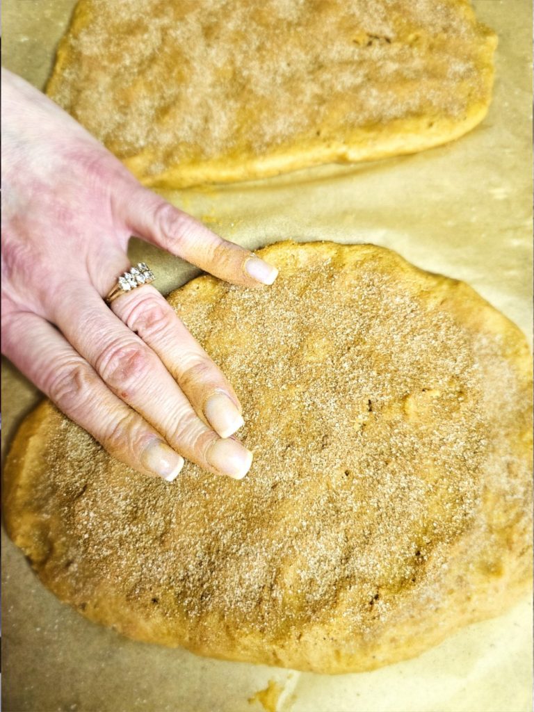 lightly-tapping-the-cinnamon-sugar-into-dough