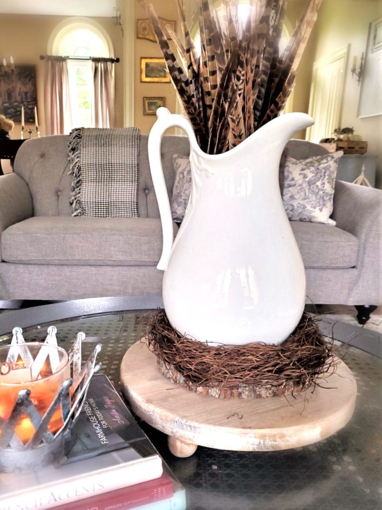 fall-centerpiece-ideas-on-a-budget-pitcher-pheasant-feathers-grapevine-base-on-wood-riser