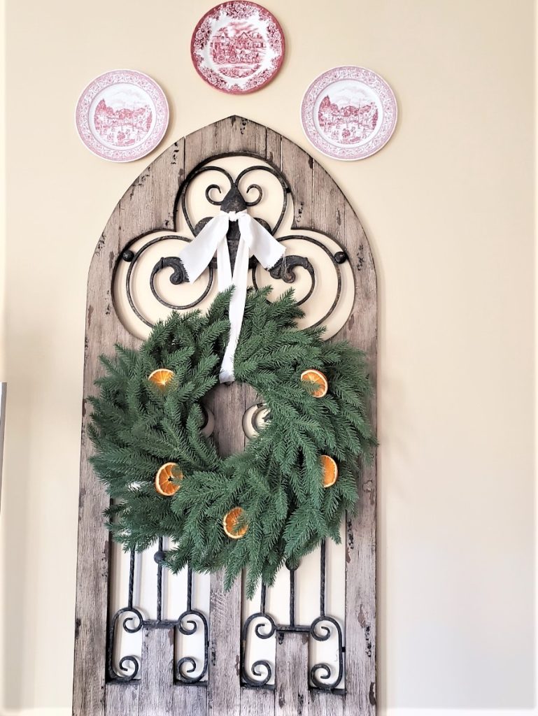 Wreath with dried orange slices on a an antique gate with satin ribbon