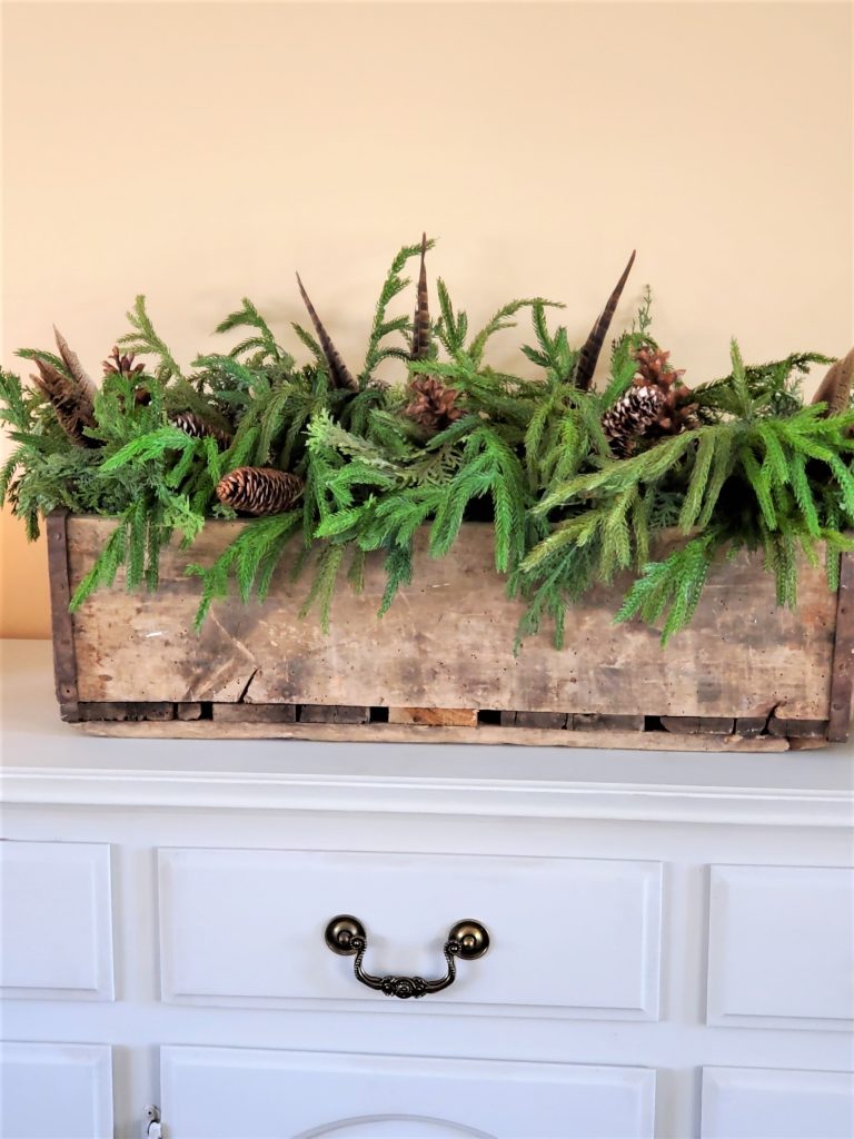 Centerpiece on Buffet Filled with Natural Greens, Pine Cones and Pheasant Feathers