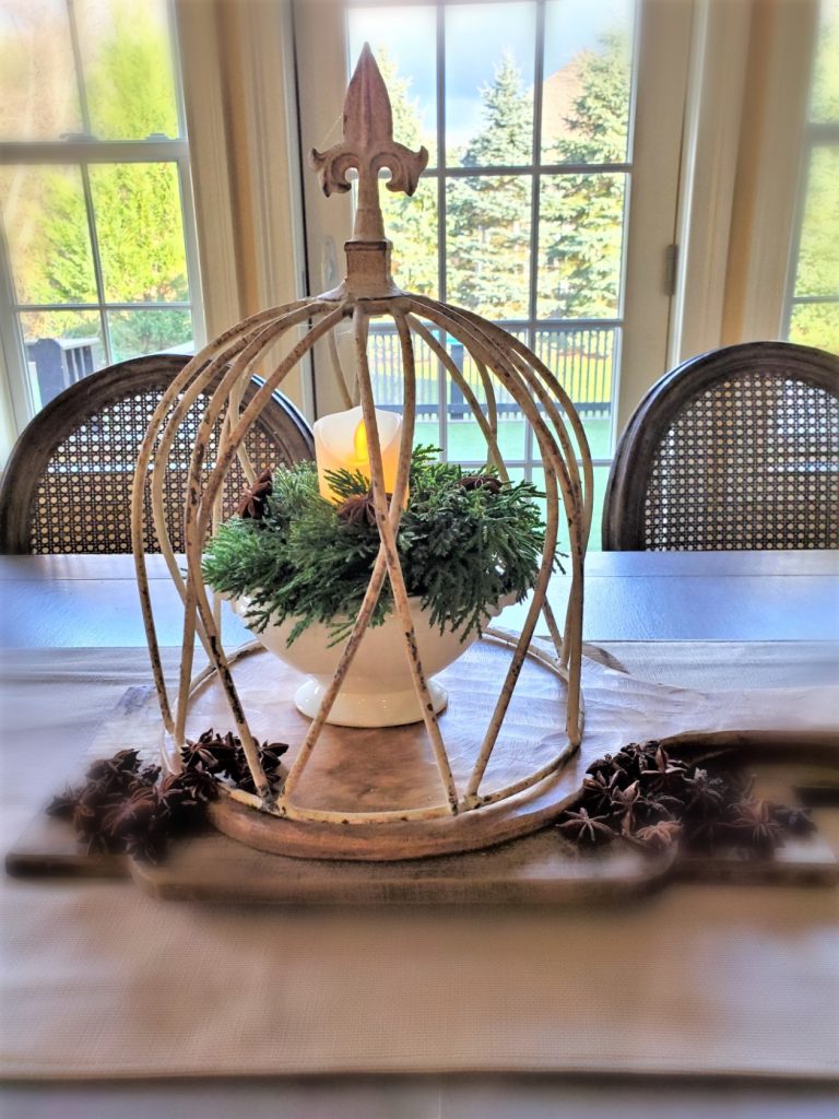 Kitchen table centerpiece star anise, breadboards, greens and lit candle for an old fashioned Christmas 