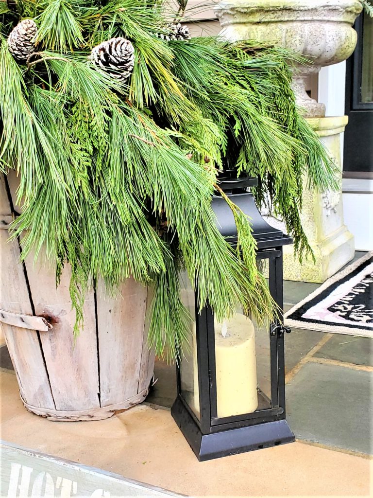 close up of basket and greenery with the smaller black lantern for the farmhouse front porch Christmas decorating ideas