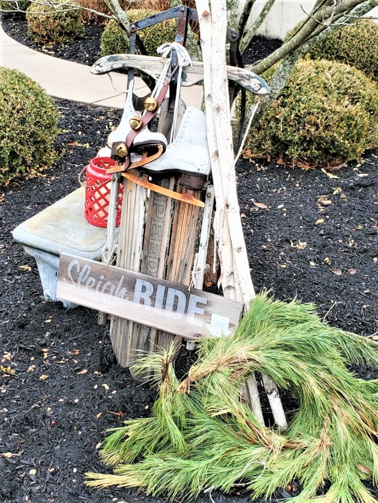 Sled during the day with greens, sled, ice skates and sleigh ride sign