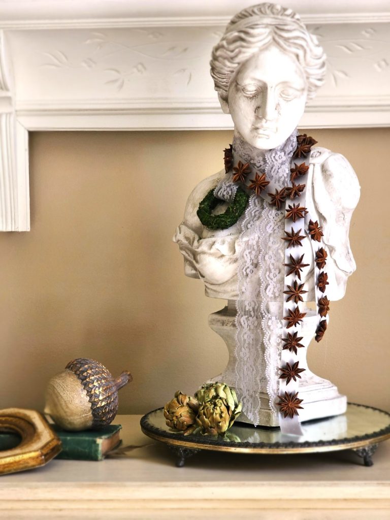 early-fall-decorating-ideas-for-a-cozy-home-now-female-bust-satin-ribbon-with-star-anise-attached-dried-artichokes-on-top-of-a-mirror