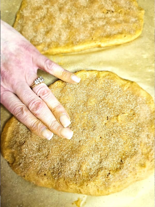 lightly-tapping-the-cinnamon-sugar-into-dough