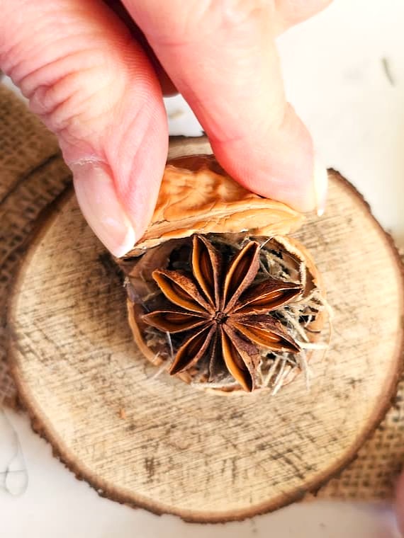 DIY-natural-wreath-with-organic-touches-me-holding-walnut-shell-to-set-to-connect-to-other-shell